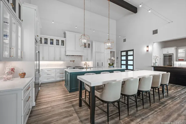 a kitchen with a dining table chairs cabinets wooden floor and appliances