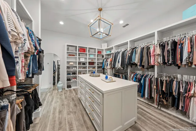 a view of a walk in closet with clothes and shoes