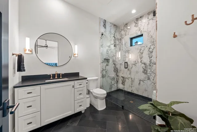 a bathroom with a granite countertop toilet a sink a mirror and a shower