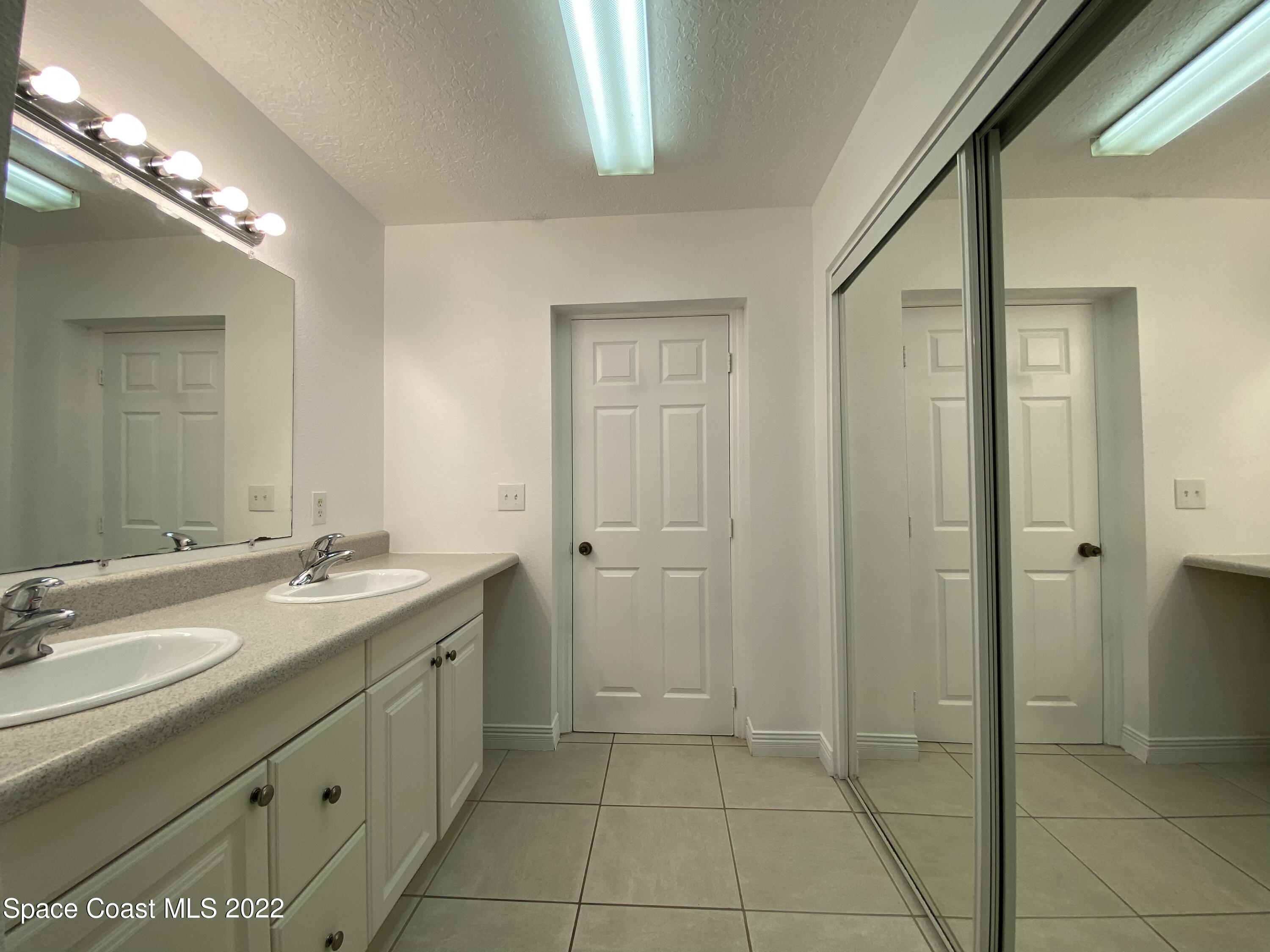 4120 Duke Street Melbourne, FL 32901 - Photo 28 of 49 a bathroom with a granite countertop sink a mirror and a shower