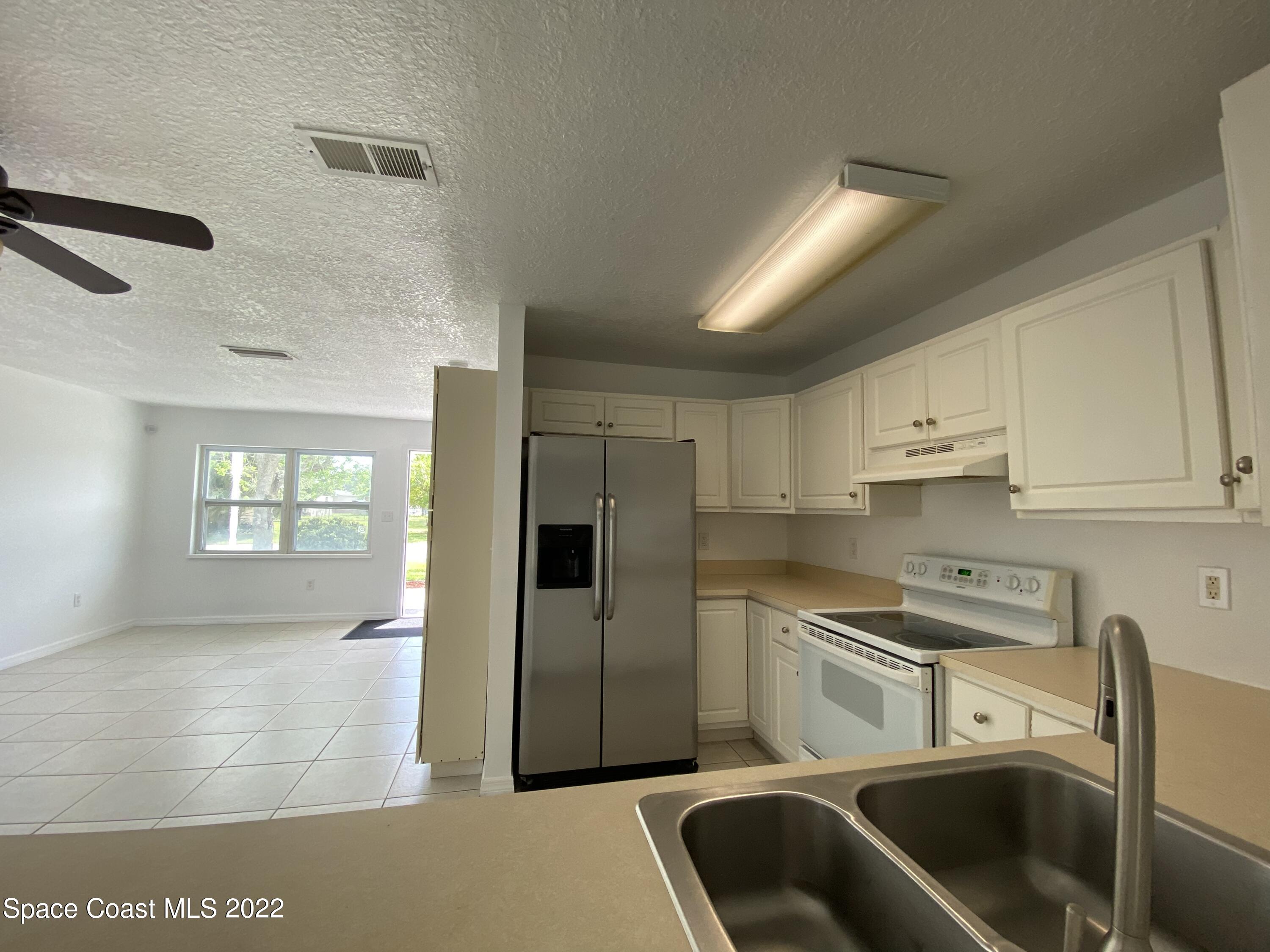 4120 Duke Street Melbourne, FL 32901 - Photo 34 of 49 a kitchen with stainless steel appliances a refrigerator a sink a stove and white cabinets
