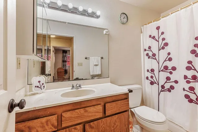 a bathroom with a granite countertop sink a toilet and a mirror