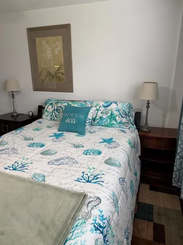 a bedroom with a bed and a lamp on dresser