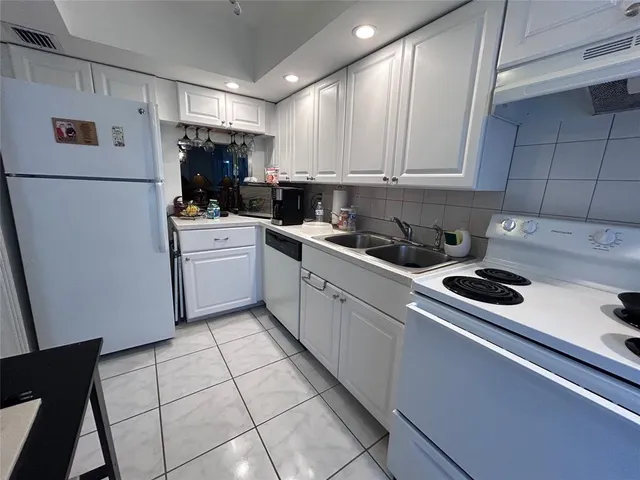 a kitchen with a sink a refrigerator and cabinets