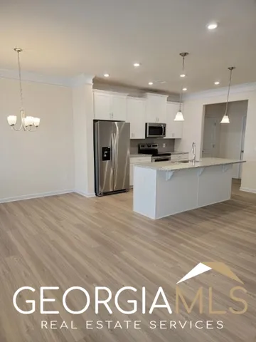 a view of kitchen with kitchen island stainless steel appliances sink and wooden floor