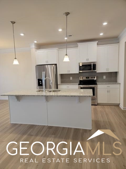 160 Madison Bend Holly Springs, GA 30188 - Photo 5 of 18 a kitchen with kitchen island granite countertop a sink a stove and a refrigerator