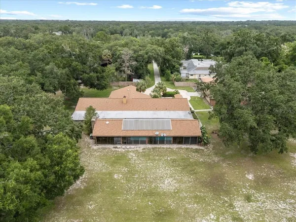 an aerial view of a house with outdoor space and trees all around