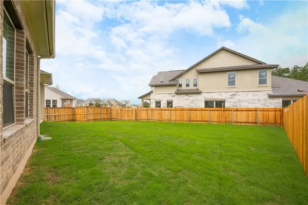 a view of a house next to a big yard and large trees