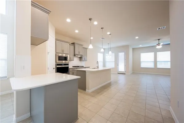 a large kitchen with kitchen island a sink a stove a refrigerator and a dining table with wooden floor