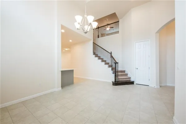a view of a hallway with staircase and a chandelier