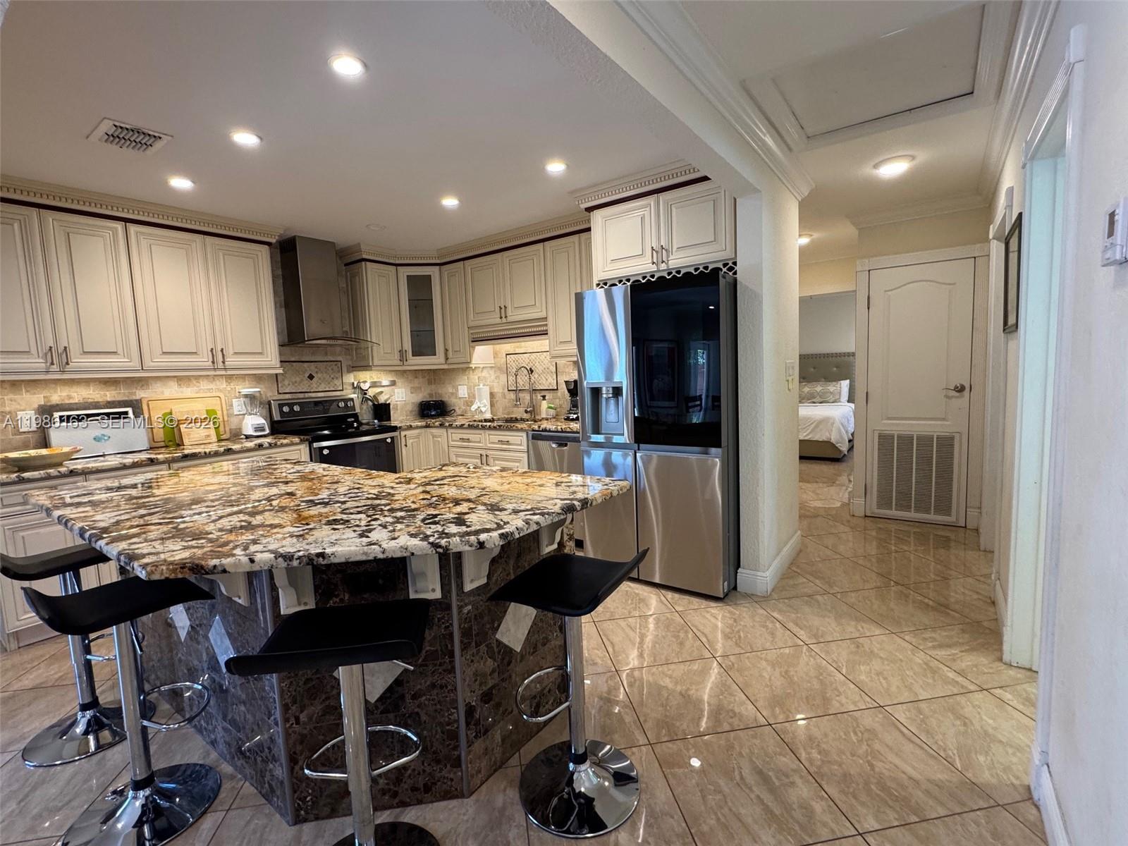 2355 Southeast 7th Street Pompano Beach, FL 33062 - Photo 9 of 31 a kitchen with stainless steel appliances granite countertop a table chairs sink refrigerator and cabinets