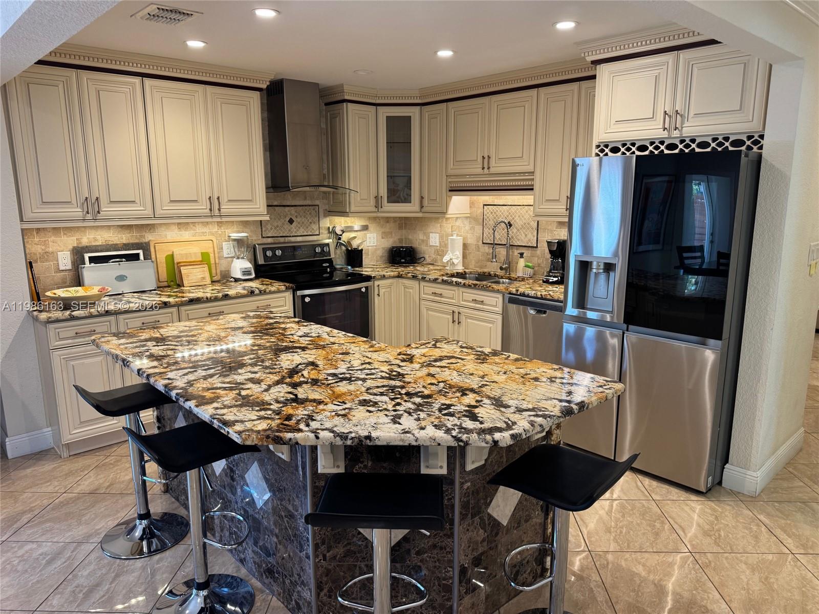 2355 Southeast 7th Street Pompano Beach, FL 33062 - Photo 10 of 31 a kitchen with stainless steel appliances granite countertop a table chairs sink refrigerator and cabinets