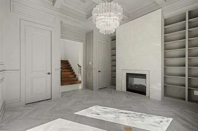 an empty room with a fireplace and chandelier