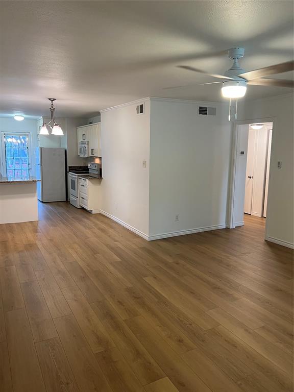 3929 Inwood Road, Unit 2021 Dallas, TX 75209 - Photo 7 of 24 Open-concept living space with wood-finish flooring, a ceiling fan with integrated lighting, and crown molding