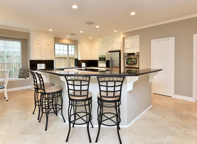 a kitchen with stainless steel appliances kitchen island granite countertop a table chairs sink and cabinets