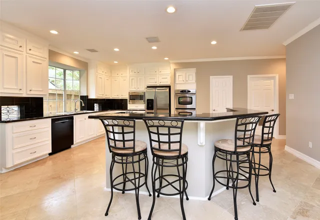 a living room with stainless steel appliances furniture a kitchen view and a living room view