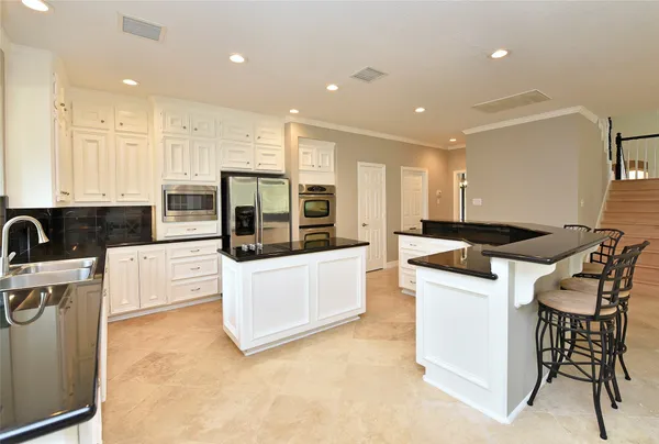 a large kitchen with stainless steel appliances a large counter top a stove a refrigerator a sink and a granite counter tops