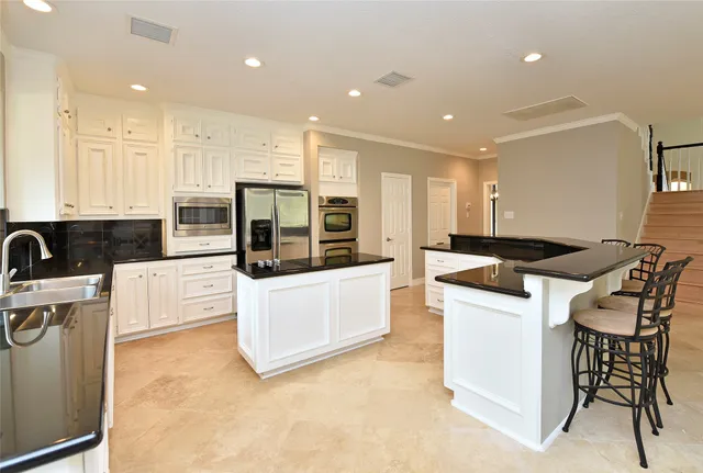 a large kitchen with stainless steel appliances a large counter top a stove a refrigerator a sink and a granite counter tops