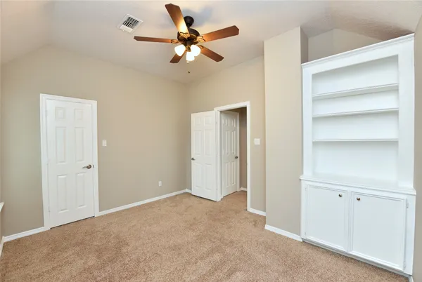 an empty room with closet and a chandelier fan