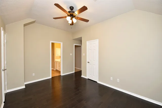 an empty room with chandelier fan and windows
