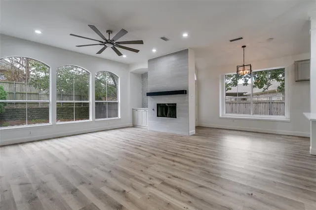 a view of an empty room with a window and wooden floor