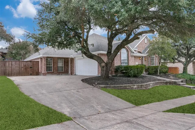 a front view of a house with garden and trees