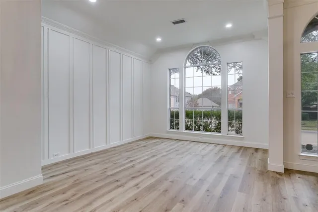 an empty room with wooden floor fan windows and outdoor view