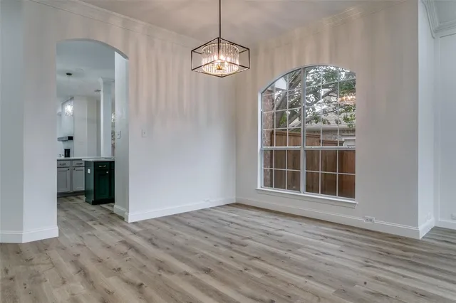 an empty room with wooden floor cabinet and windows