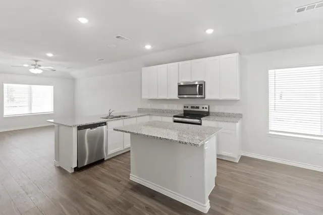 a kitchen with granite countertop white cabinets and black stainless steel appliances