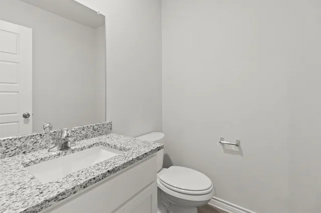 a bathroom with a granite countertop sink and a toilet