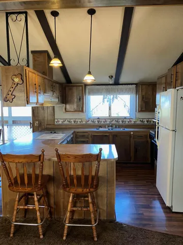 a kitchen with stainless steel appliances granite countertop a refrigerator a sink dishwasher a stove and white countertops with wooden floor