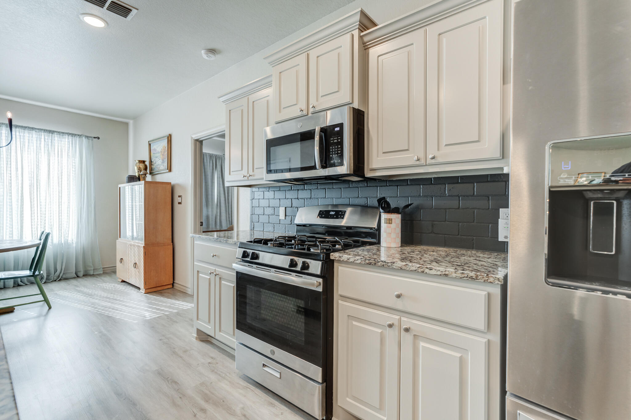 7813 88th Street Lubbock, TX 79424 - Photo 4 of 21 a kitchen with stainless steel appliances granite countertop a stove a refrigerator and a microwave