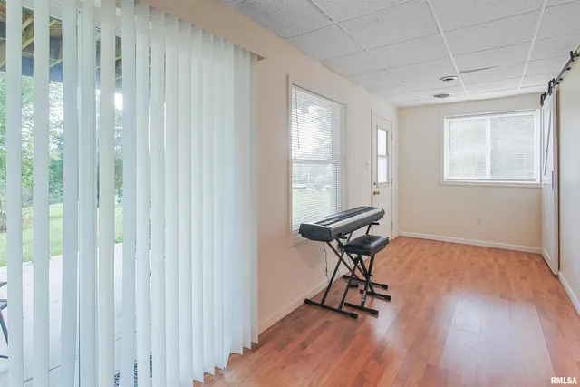 a room with gym equipment on wooden floor and a window
