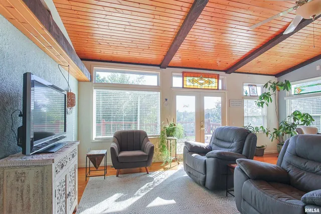 a living room with furniture a flat screen tv and floor to ceiling window