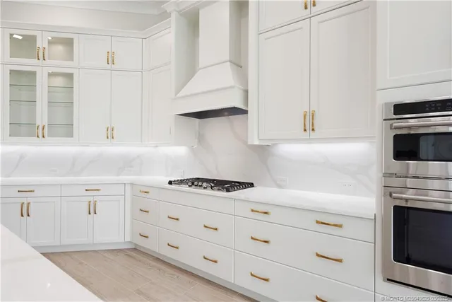 a large white kitchen with a lot of counter space and wooden floor