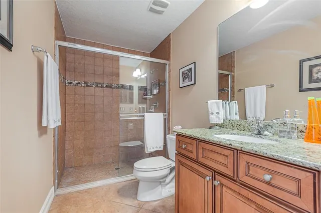 a bathroom with a granite countertop sink toilet a mirror and shower