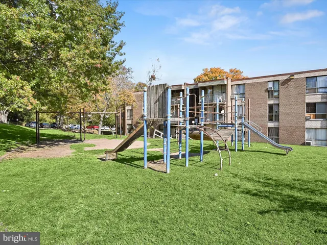 a view of a backyard with a slide trees and wooden fence