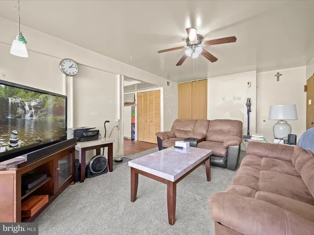 a living room with furniture a ceiling fan and a flat screen tv
