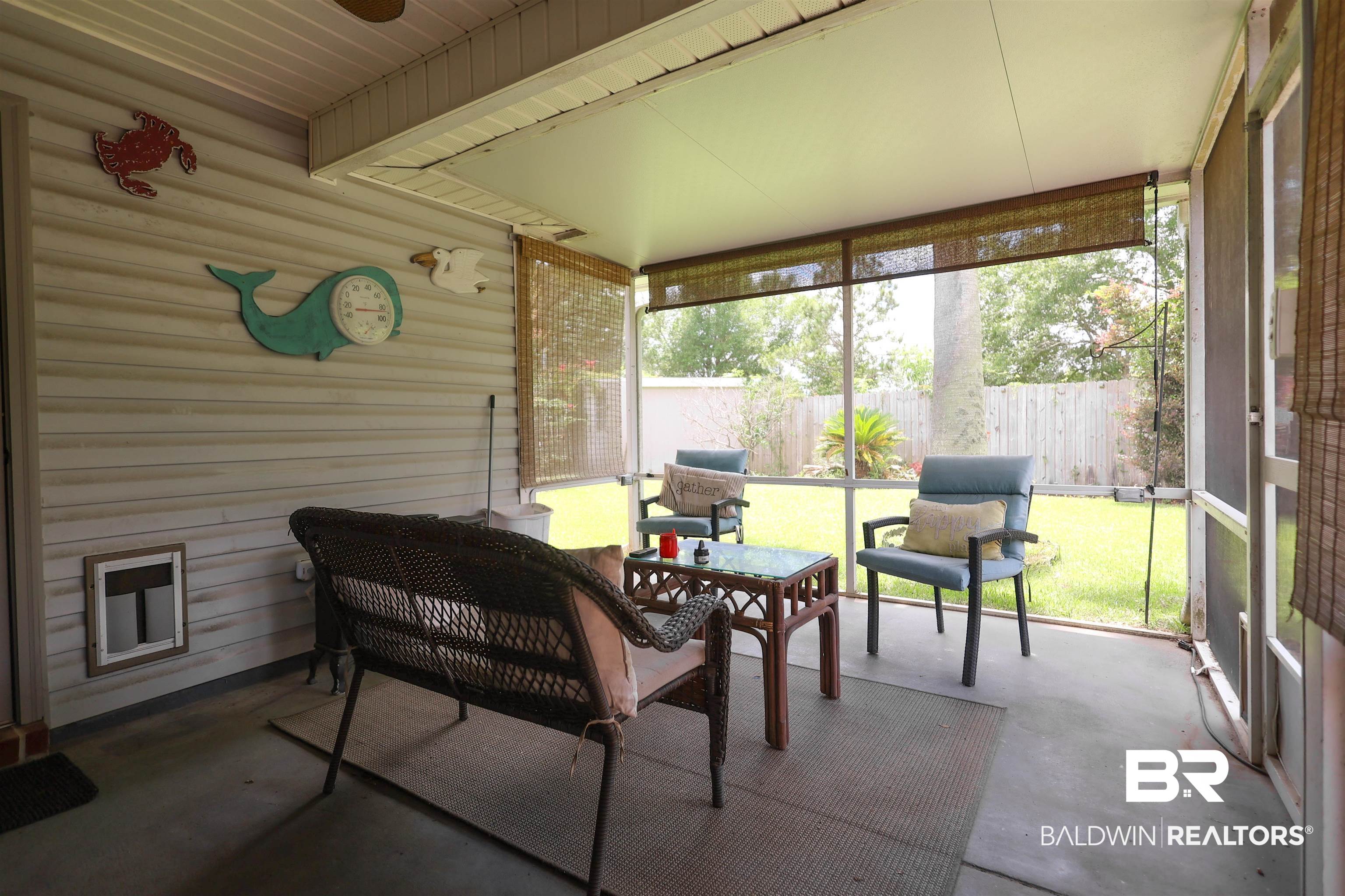 7790 Audubon Drive Foley, AL 36535 - Photo 34 of 39 Screened patio with a concrete floor, featuring a white vinyl-sided exterior wall and bamboo roll-up blinds