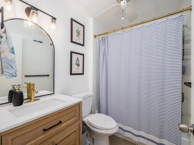 a bathroom with a granite countertop sink toilet and mirror