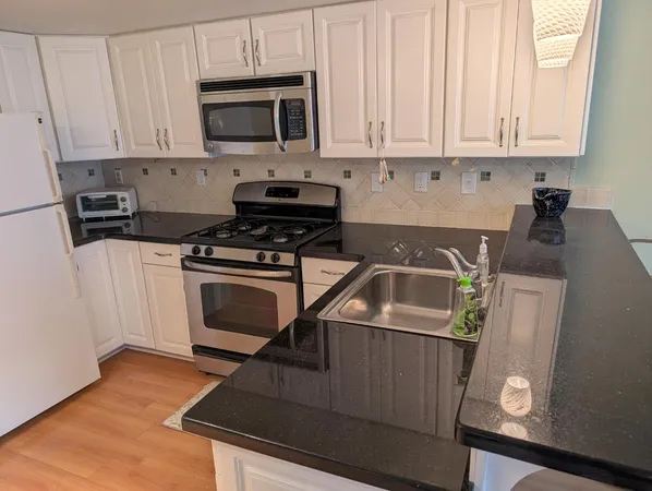 a kitchen with granite countertop a stove a microwave a sink and cabinets