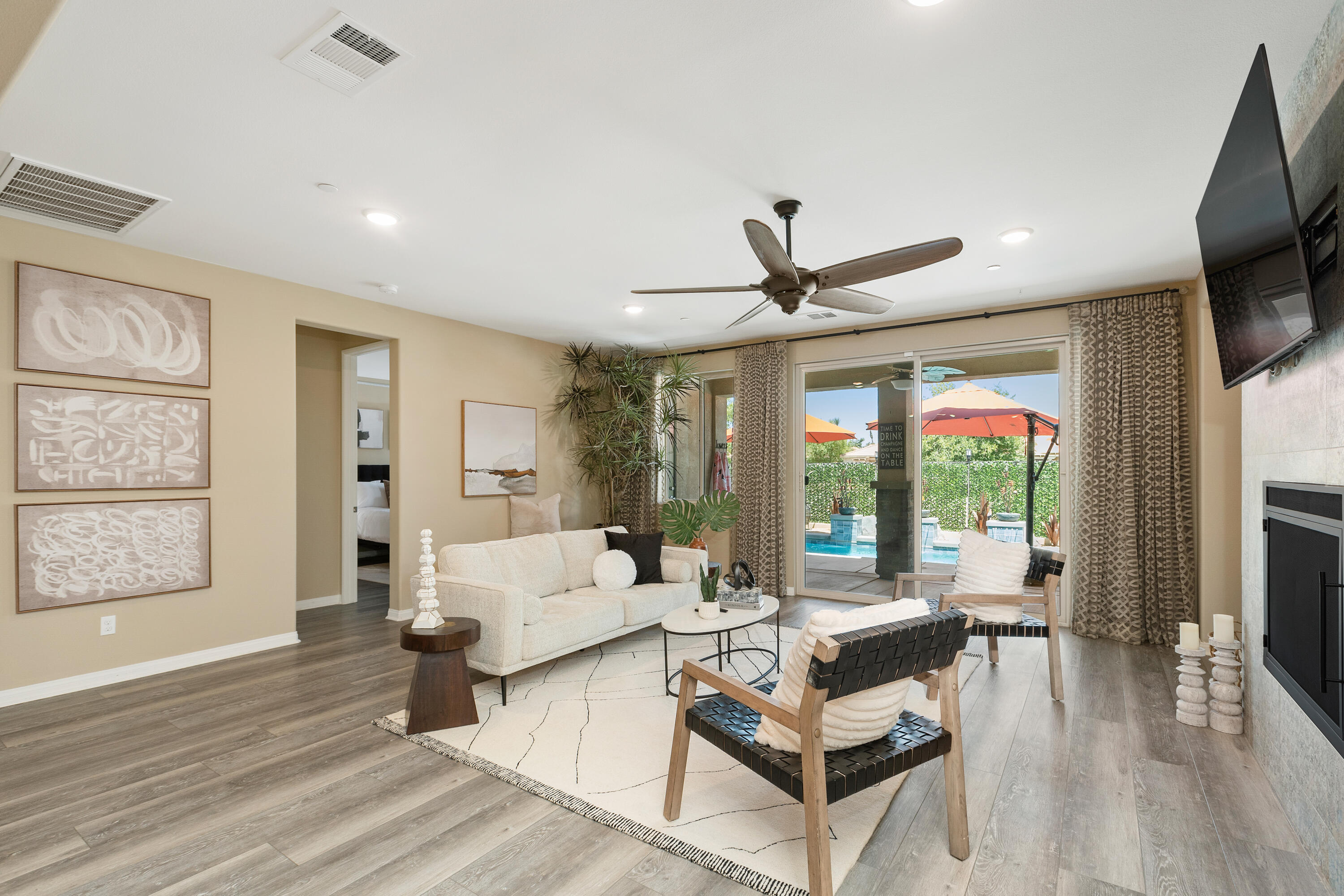 82700 Burnette Drive Indio, CA 92201 - Photo 11 of 38 a living room with furniture a ceiling fan a flat screen tv and a large window