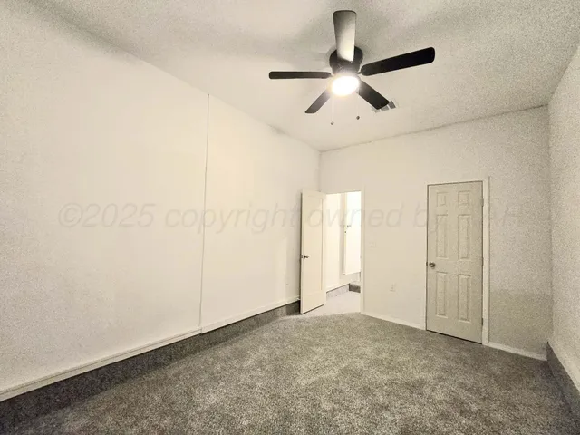 en empty room with ceiling fan and window