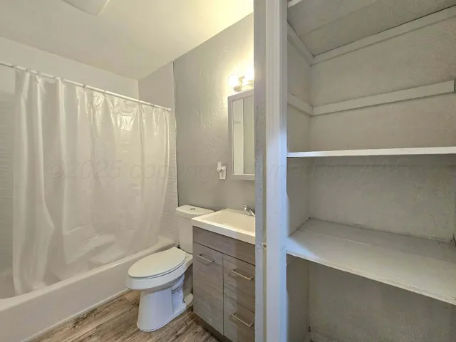 a bathroom with a granite countertop bathtub shower sink vanity and toilet