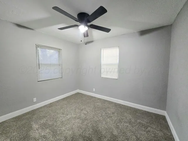 an empty room with a window and a fan
