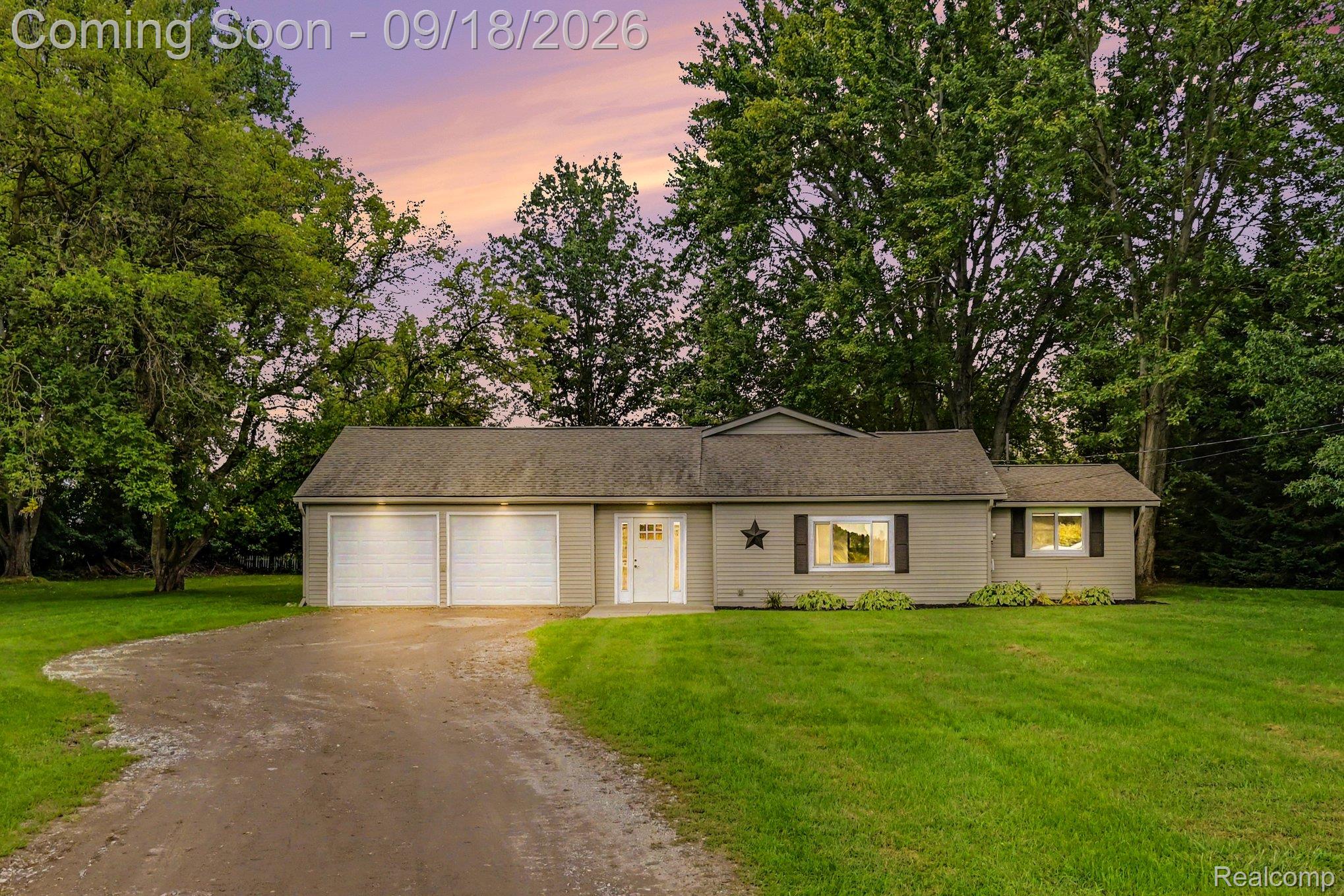 Ranch-style residence featuring a gravel driveway, two-car garage, and mature trees