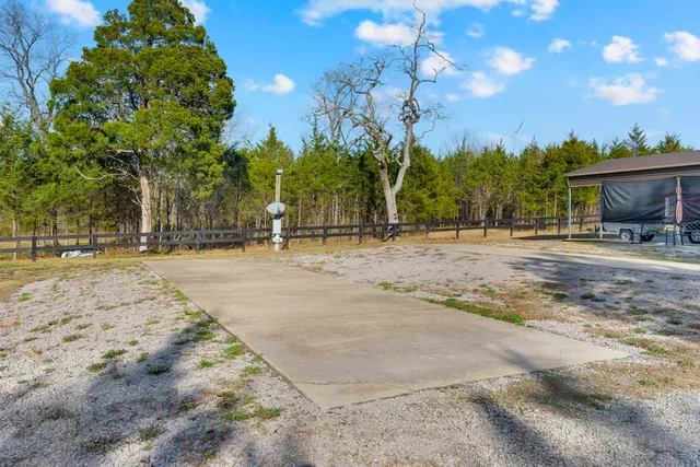a backyard of a house with table and chairs under an umbrella