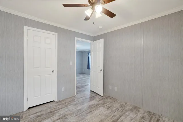 an empty room with wooden floor and ceiling fan