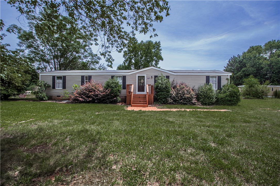 Well-maintained manufactured home nestled amidst lush green landscaping, offering a serene residential retreat.