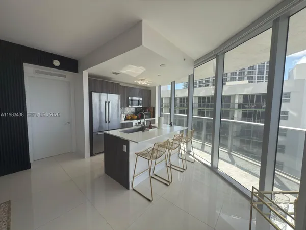 a kitchen with stainless steel appliances kitchen island granite countertop a refrigerator and a sink